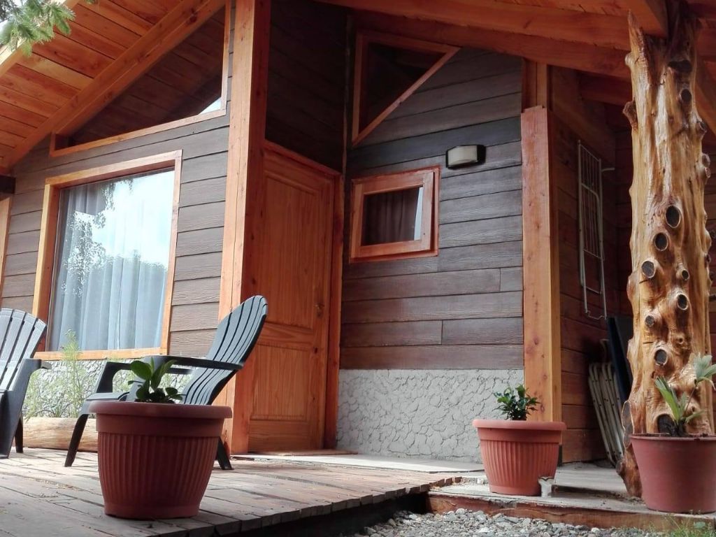 Porche de madera de una cabaña, con deck y plantas