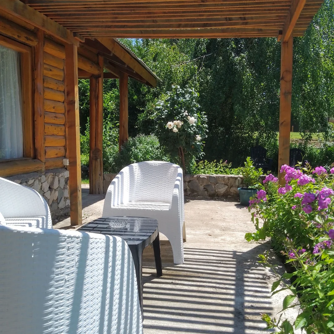 Galería de la cabaña con sillones blancos y flores