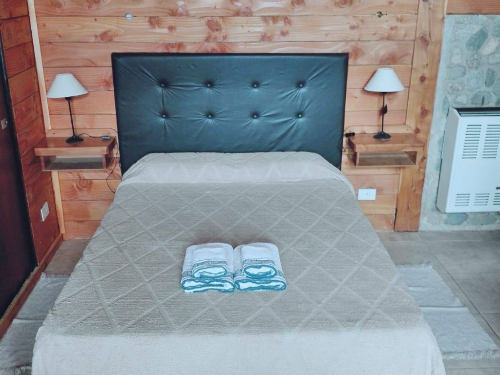 Dormitorio con cama matrimonial y mesas de luz de madera